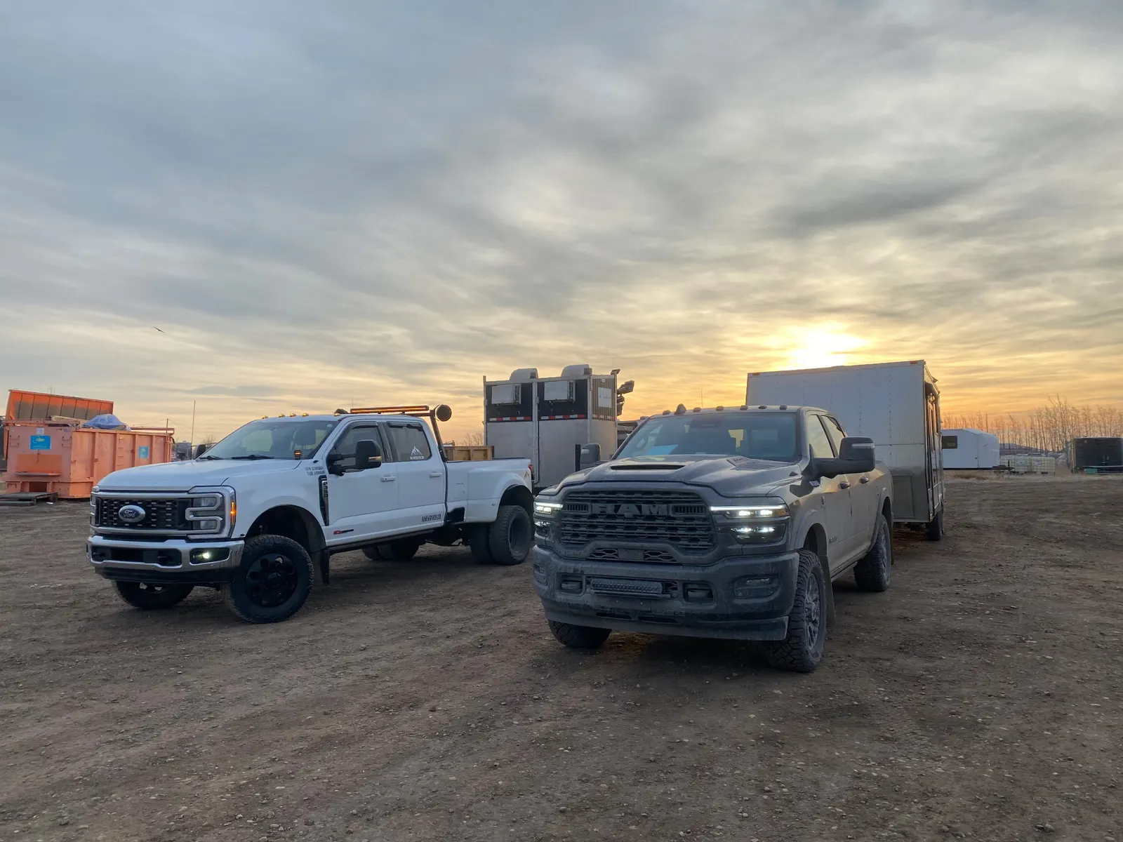 Nash Services dually trucks and equipment trailers at sunset on an Alberta lease site